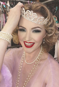 English blonde girl wearing a diamond encrusted tiara and smiling